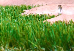 hand moving through artificial grass blades