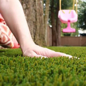 childs hand touching artficial grass