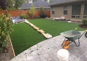 installing artificial grass in home owners backyard